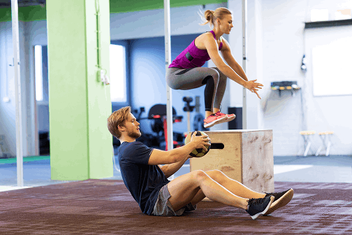 fitness-sport-training-exercising-people-concept-woman-man-with-medicine-ball-doing-curl-ups-box-jumps-gym 1